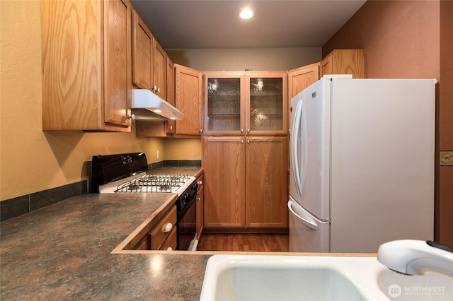 kitchen with white fridge, wood-type flooring, and black range with gas cooktop