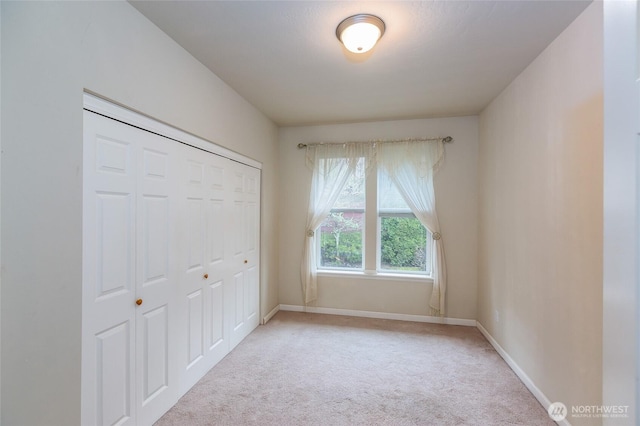 unfurnished bedroom featuring a closet and light colored carpet