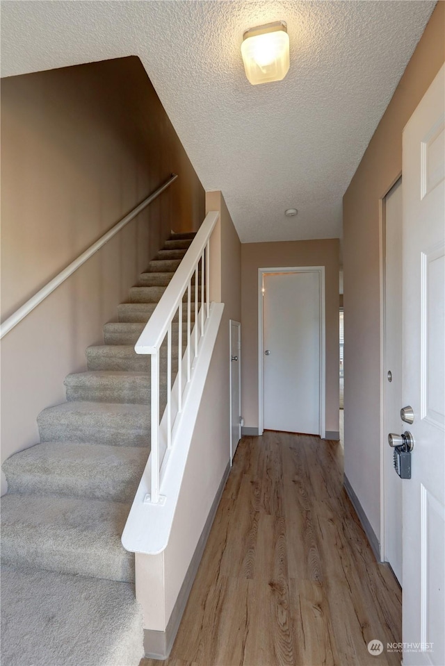 staircase featuring wood-type flooring and a textured ceiling