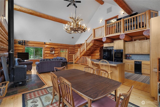 dining room with beam ceiling, a wood stove, log walls, light hardwood / wood-style flooring, and high vaulted ceiling