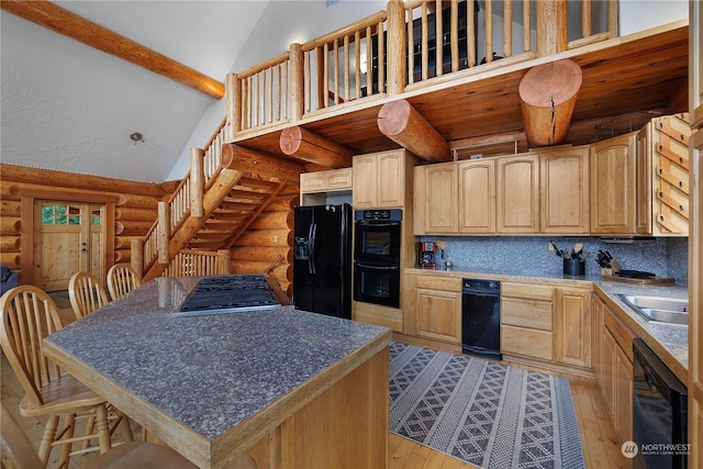 kitchen with tasteful backsplash, rustic walls, a breakfast bar, black appliances, and a kitchen island