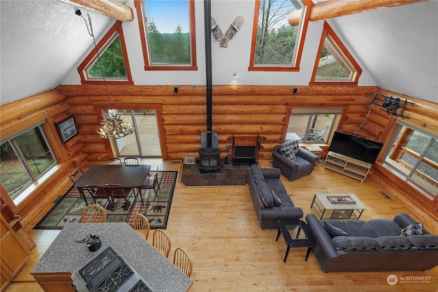 living room with a wood stove, log walls, and an inviting chandelier