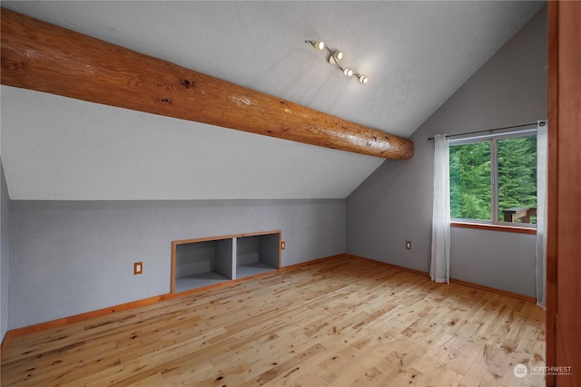 additional living space featuring light wood-type flooring and lofted ceiling with beams