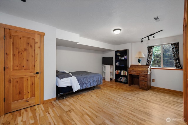 bedroom featuring light hardwood / wood-style floors and track lighting