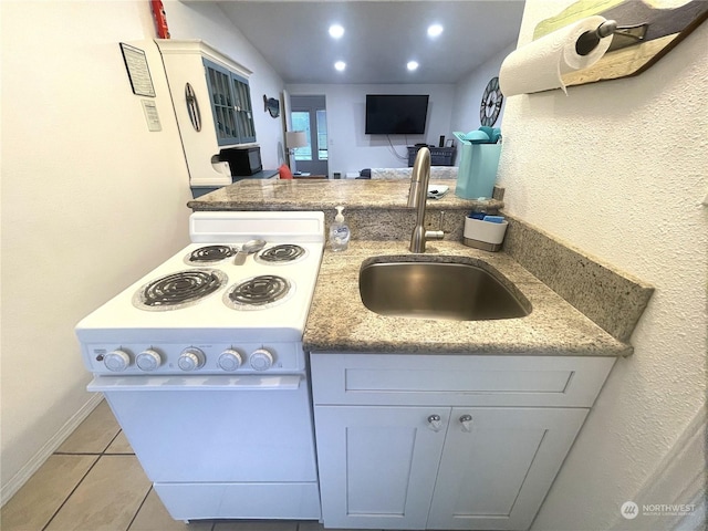 kitchen with white electric range oven, light tile patterned floors, sink, and dark stone counters