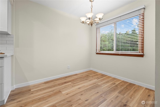 unfurnished dining area featuring a notable chandelier and light hardwood / wood-style flooring