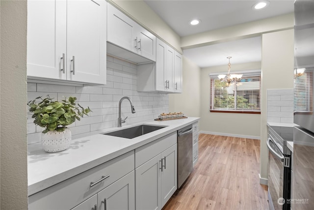 kitchen with sink, hanging light fixtures, white cabinetry, and appliances with stainless steel finishes