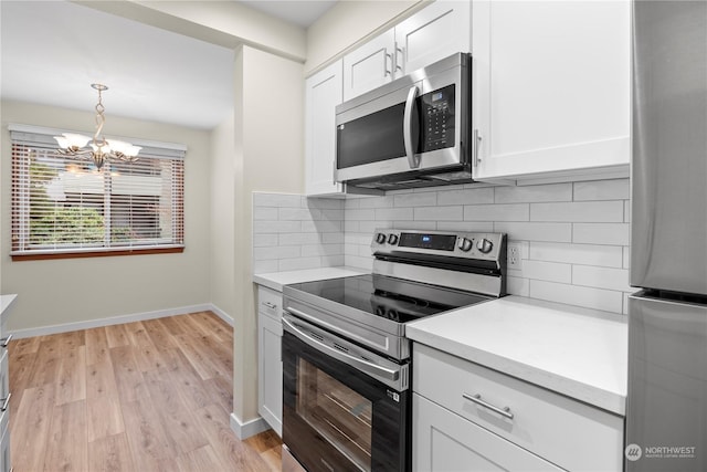 kitchen with stainless steel appliances, white cabinetry, backsplash, hanging light fixtures, and a notable chandelier