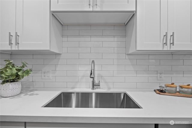 kitchen with sink, white cabinets, light stone counters, and decorative backsplash