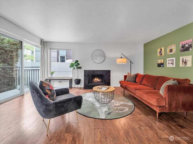 living room with wood-type flooring and a tiled fireplace