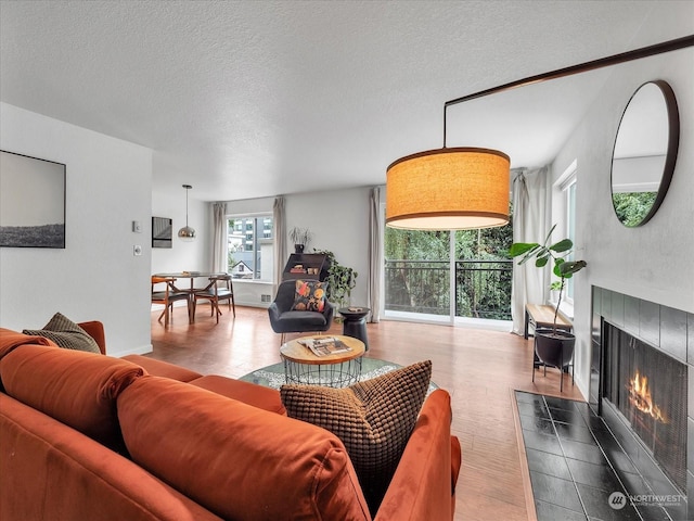 living room with a textured ceiling and a tiled fireplace