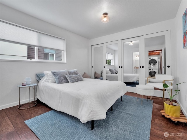 bedroom featuring french doors, stacked washer and dryer, and dark wood-type flooring