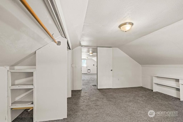 bonus room featuring a textured ceiling, dark carpet, and lofted ceiling