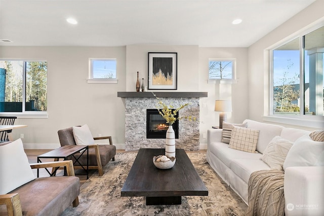 living room with a stone fireplace and light wood-type flooring