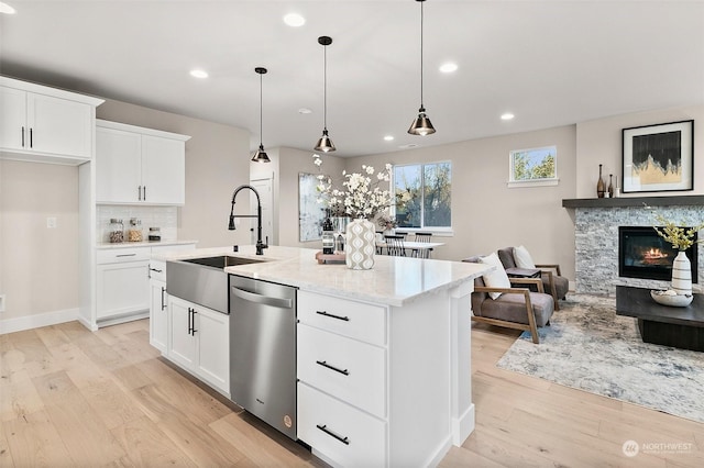 kitchen featuring white cabinetry, stainless steel dishwasher, a kitchen island with sink, and hanging light fixtures