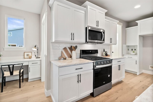 kitchen featuring light stone counters, stainless steel appliances, white cabinets, and light wood-type flooring