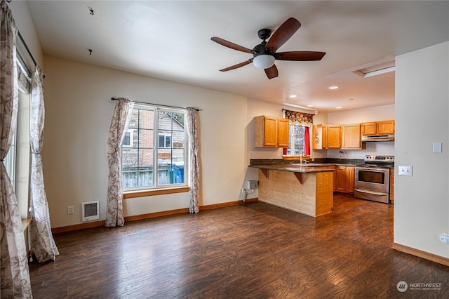 kitchen featuring ceiling fan, kitchen peninsula, a breakfast bar area, dark hardwood / wood-style floors, and electric range