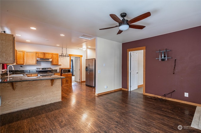 kitchen with kitchen peninsula, decorative light fixtures, a breakfast bar, appliances with stainless steel finishes, and sink