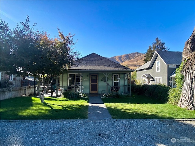 bungalow-style home featuring a front yard, covered porch, and a mountain view