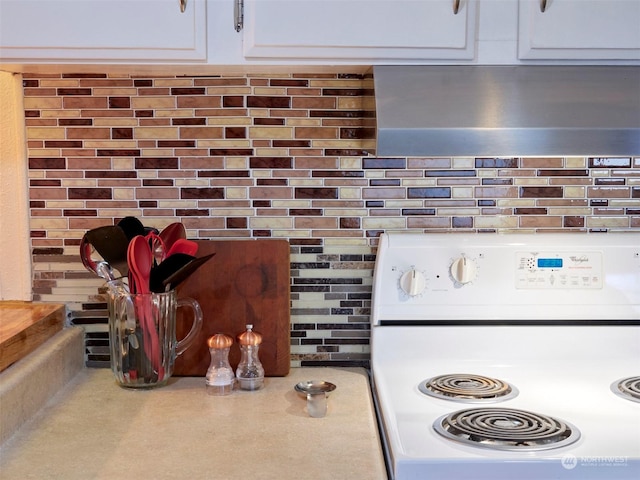 kitchen featuring stove, white cabinetry, and backsplash