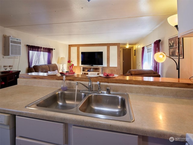 kitchen with plenty of natural light, dishwasher, sink, and a wall unit AC