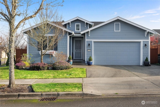 view of front of home featuring a front yard, concrete driveway, an attached garage, and fence