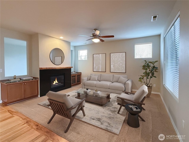 living room featuring a wealth of natural light, visible vents, baseboards, and a glass covered fireplace