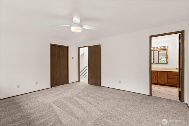 unfurnished bedroom with light carpet, a sink, ensuite bath, and ceiling fan