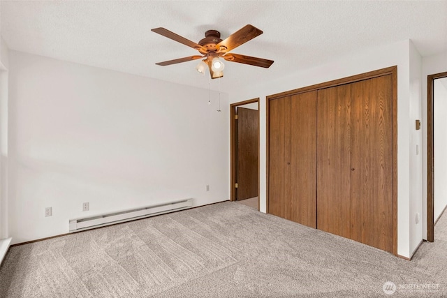 unfurnished bedroom with a closet, baseboard heating, a textured ceiling, and light colored carpet