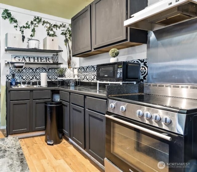 6807 345th St S, Roy, WA 98580 - kitchen with light wood-type flooring, black microwave, stainless steel range with electric stovetop, under cabinet range hood, and decorative backsplash