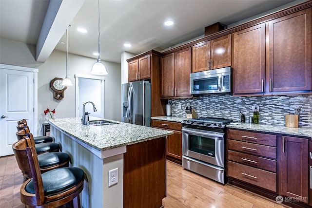 kitchen with decorative light fixtures, light stone countertops, a breakfast bar, and appliances with stainless steel finishes