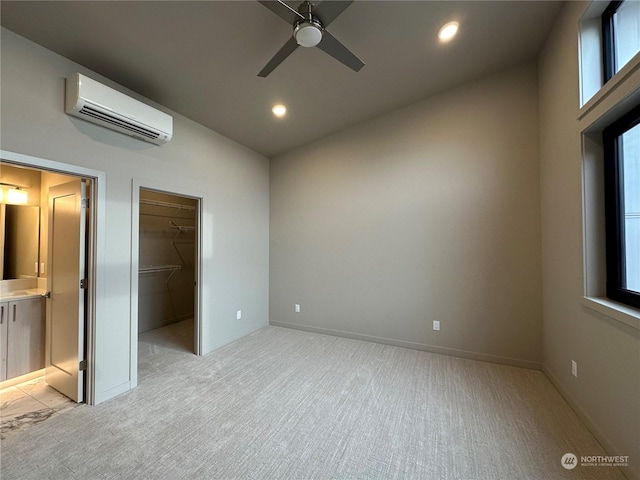 interior space with multiple windows, light colored carpet, a spacious closet, and a wall unit AC