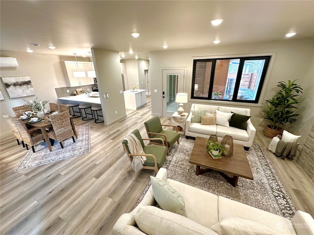 living room featuring a wall mounted air conditioner and light wood-type flooring