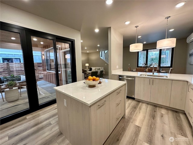 kitchen with pendant lighting, dishwasher, sink, a center island, and light hardwood / wood-style floors