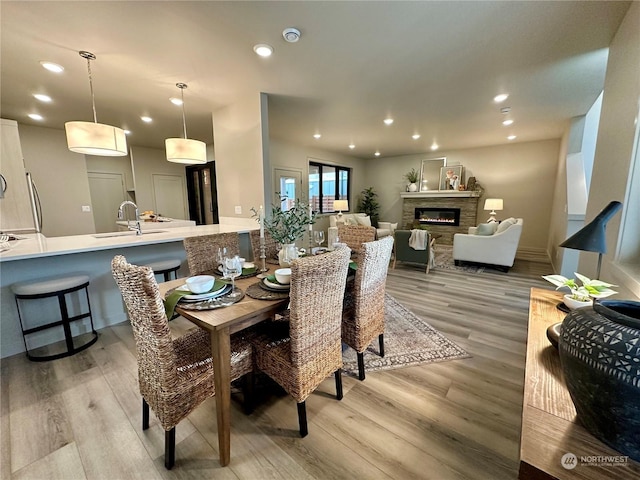 dining area featuring a stone fireplace, sink, and light hardwood / wood-style floors