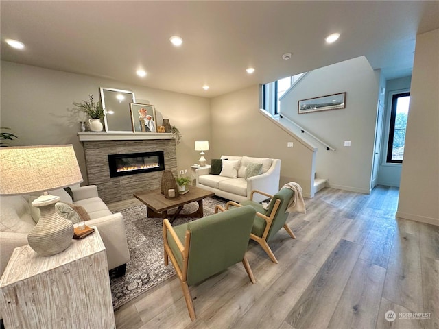 living room with a stone fireplace and light hardwood / wood-style floors