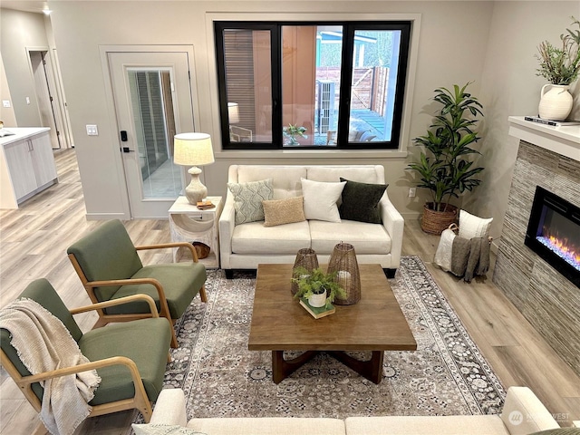 living room with a tiled fireplace and light hardwood / wood-style flooring