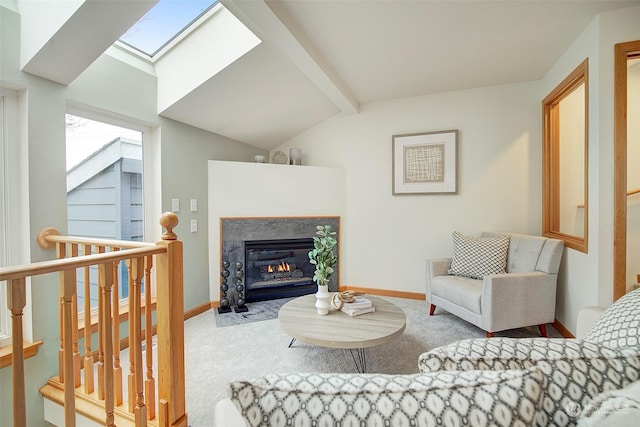 carpeted living room with a fireplace and vaulted ceiling with skylight