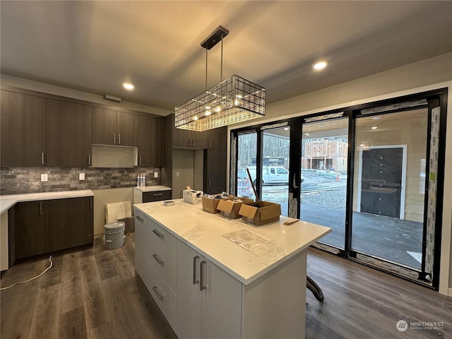 kitchen featuring backsplash, hanging light fixtures, dark brown cabinets, a kitchen island, and dark hardwood / wood-style flooring