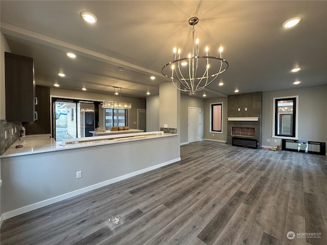 kitchen with a fireplace, hardwood / wood-style floors, hanging light fixtures, dark brown cabinetry, and a notable chandelier