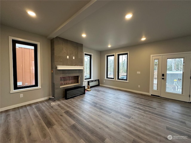 unfurnished living room featuring a large fireplace, plenty of natural light, and hardwood / wood-style flooring