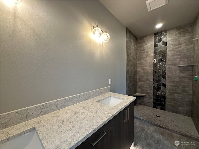 bathroom featuring a tile shower and vanity