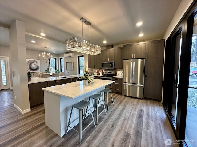 kitchen with pendant lighting, dark brown cabinets, stainless steel appliances, a wall mounted air conditioner, and kitchen peninsula