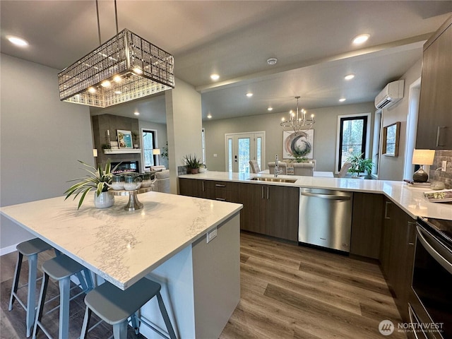 kitchen with appliances with stainless steel finishes, a wall mounted air conditioner, sink, a kitchen bar, and a center island