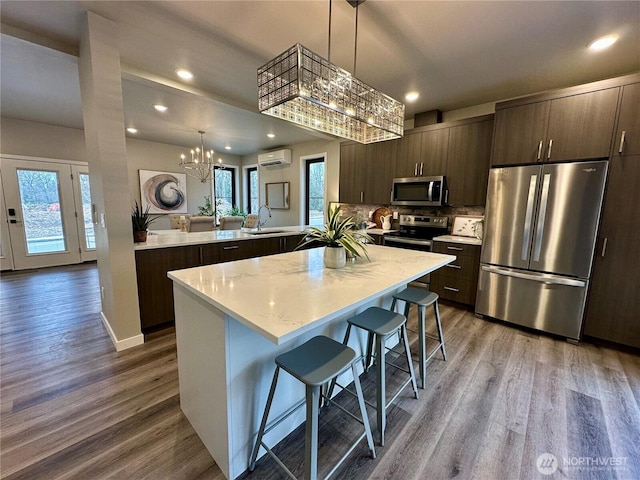 kitchen featuring appliances with stainless steel finishes, an AC wall unit, a breakfast bar area, kitchen peninsula, and an inviting chandelier