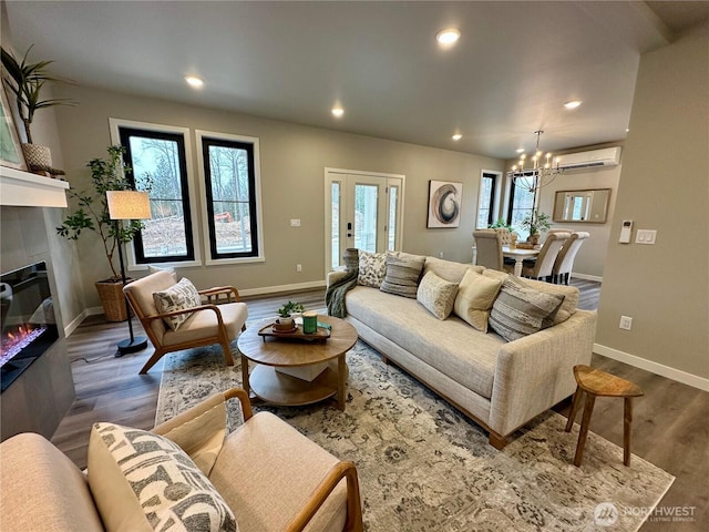 living room with a tile fireplace, an AC wall unit, dark hardwood / wood-style floors, and an inviting chandelier