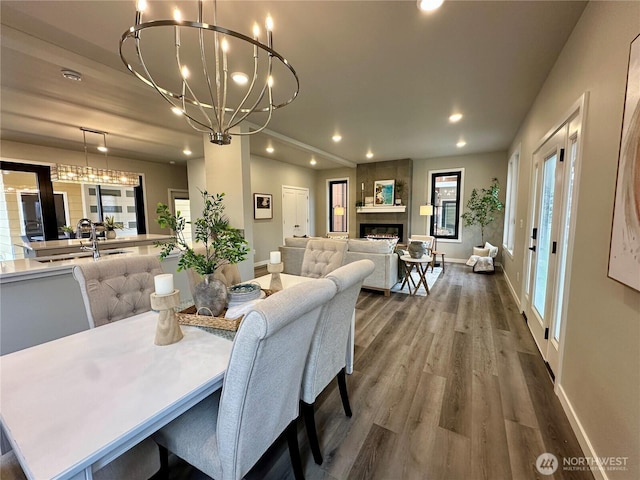 dining space featuring a notable chandelier, a fireplace, sink, and wood-type flooring