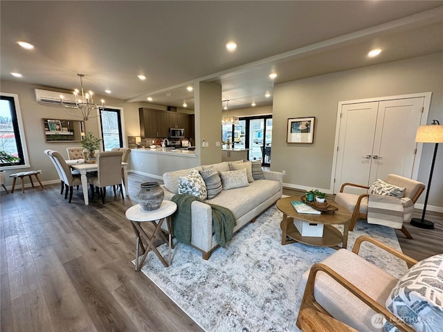 living room featuring an inviting chandelier, a wall mounted air conditioner, and dark hardwood / wood-style flooring