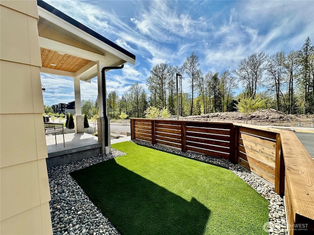 view of yard with covered porch and fence
