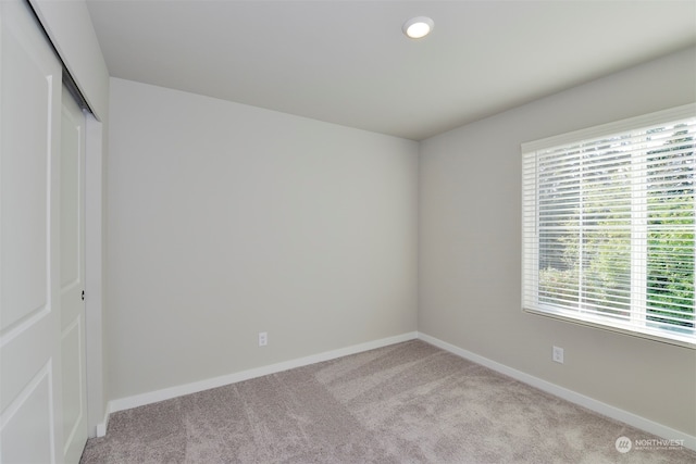 unfurnished bedroom with light carpet and a closet